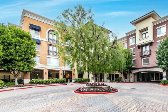 Front view of a multi-story building with a central tree and circular driveway.
