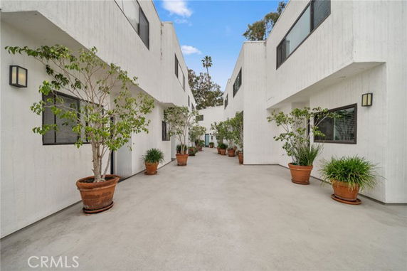 View of a building complex with white painted exterior walls and potted plants lining the pathway.
