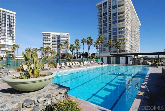 Outdoor swimming pool area with high-rise buildings in the background.