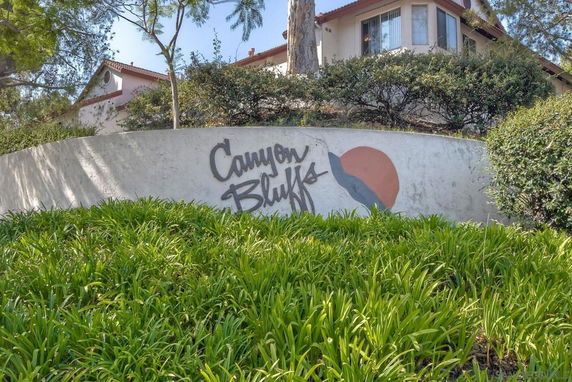 Front view of a house with red-tiled roof and wall with 'Canyon Bluffs' sign.