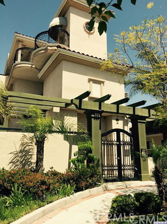 Front view of a multi-story house with a balcony and gated entrance.