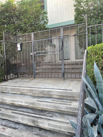 Front view of a building entrance with stairs and a metal gate.