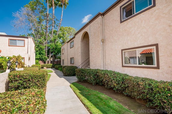 Front view of a multi-story residential building with stucco exterior and arched entryway.