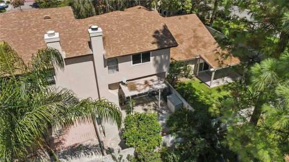 Aerial view of a two-story house with a brown roof and a covered patio.