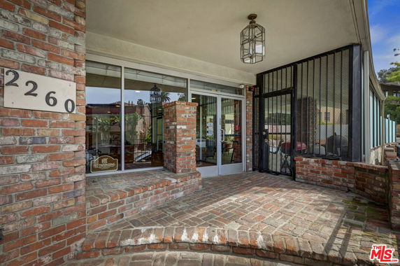 Front view of a brick entrance with steps and glass doors.
