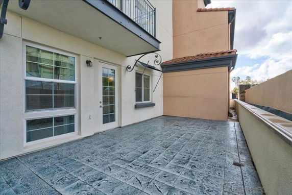 Front view of a house with a patio area and large windows.