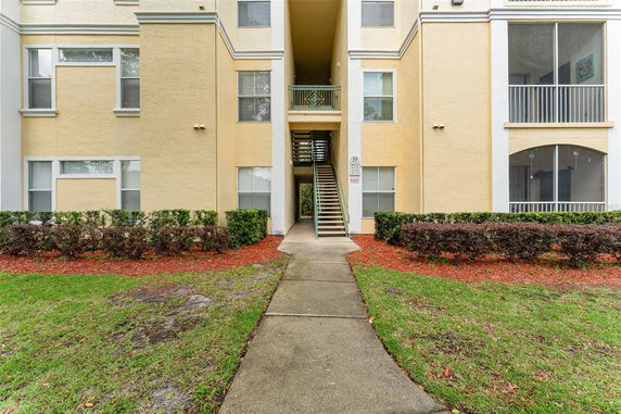 Front view of a multi-story apartment building with external stairs and a central passageway.