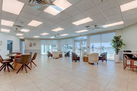 Indoor room with multiple seating areas and large windows.