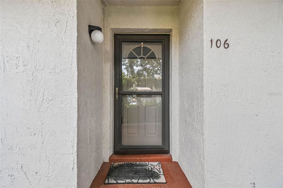 Entryway of a house with a gray door and a side wall light.