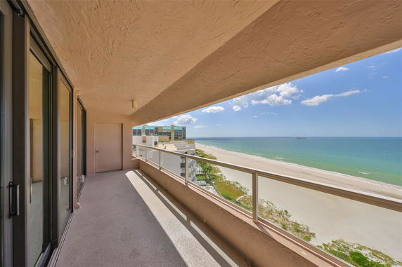 Balcony view overlooking a sandy beach and ocean.