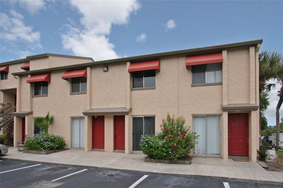 Front view of a two-story apartment building with red doors and window awnings.