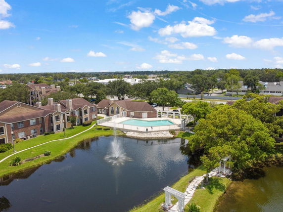Aerial view of an apartment complex with a swimming pool and a pond with a fountain.