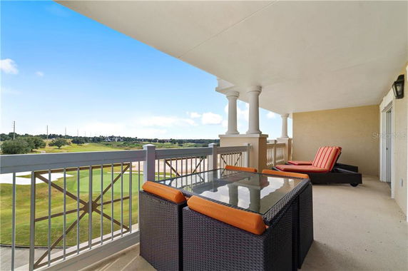 Covered balcony with outdoor furniture overlooking a golf course.
