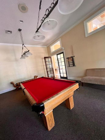 Room with a red felt pool table and seating area.