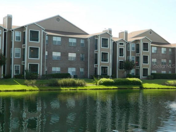 Front view of a multi-story residential building with large windows by a pond.