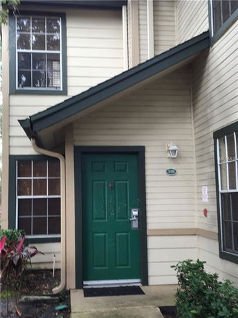 Front view of a multi-story house entrance with a green door and windows on either side.