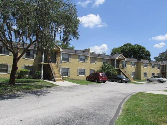 Front view of a two-story apartment building with yellow exterior and staircases.