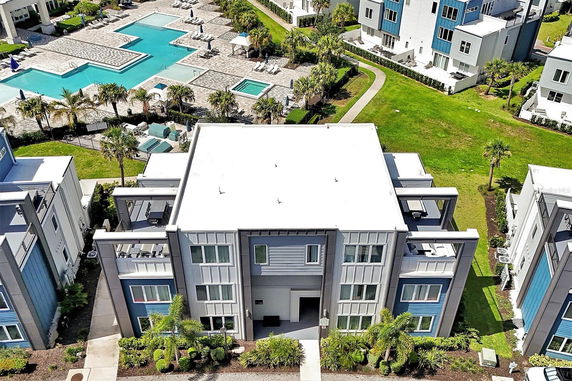 Aerial view of a modern residential complex with a swimming pool and surrounding greenery.