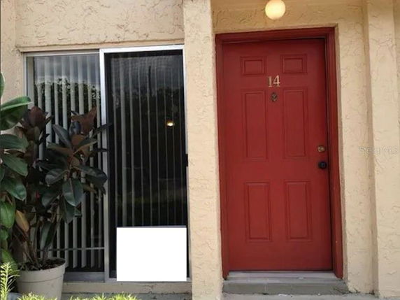 Front view of a house with a red door and sliding glass window.