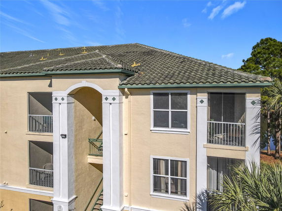 Front view of a multi-story building with balconies and a tiled roof.