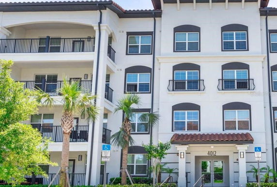 Front view of a multi-story residential building with balconies and arched windows.