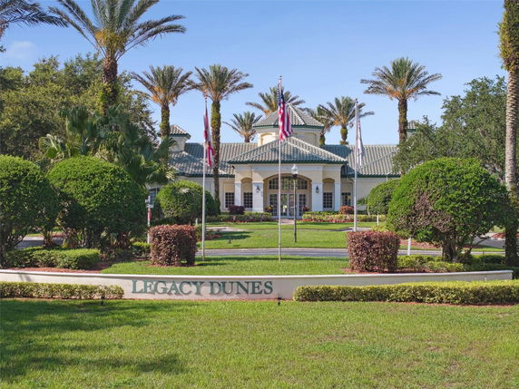 Front view of a building with a green-tiled roof, surrounded by palm trees and manicured hedges.