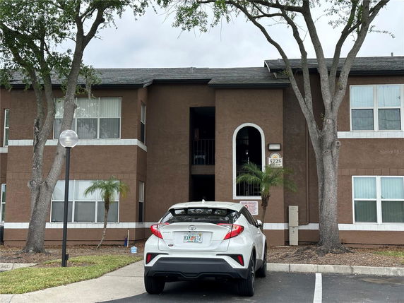 Front view of a two-story building with a central entrance and parked car in front.