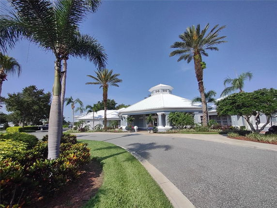 Front view of a building with a white roof and palm trees surrounding it.