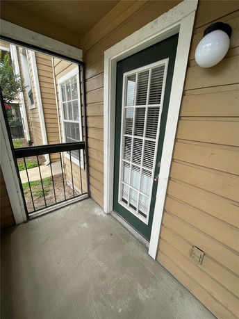 Exterior view of a building corner with a door featuring multiple glass panels and surrounding beige siding.