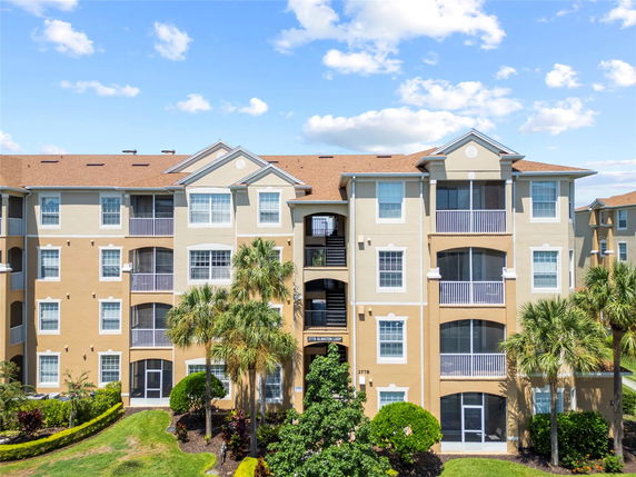 Front elevation of a multi-story apartment building with balconies and a brown roof.