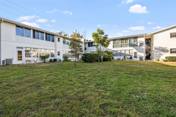 Rear view of a two-story building with large windows and a grass lawn.