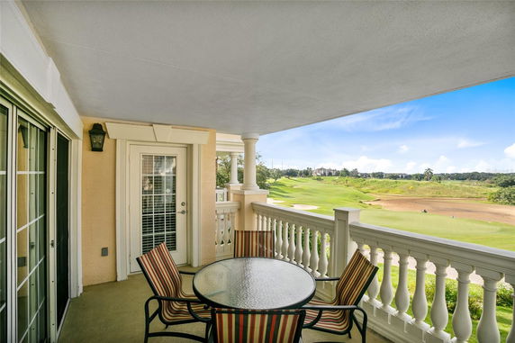 Outdoor balcony with table and chairs overlooking a golf course.