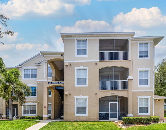 Front view of a multi-story apartment building with balconies and large windows.
