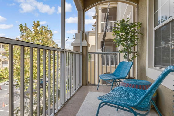 Balcony view with outdoor chairs and railing overlooking surrounding buildings and trees.