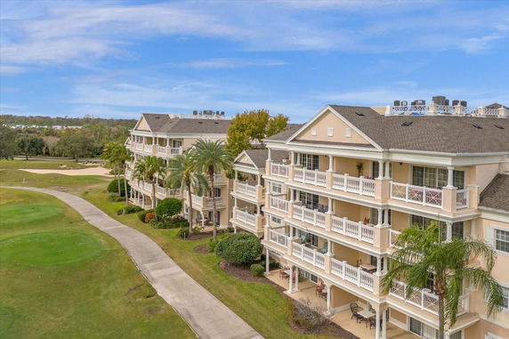 Elevated view of a multi-story residential building with balconies, surrounded by landscaped grounds and a walking path.