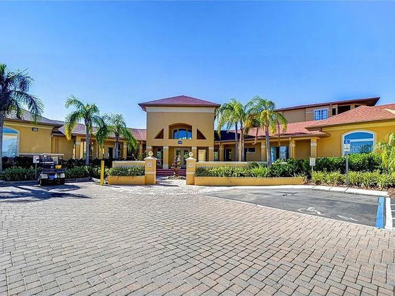 Front view of a large building with palm trees and paved driveway.