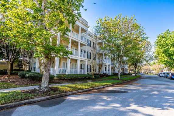 Front view of a multi-story residential building with balconies and trees lining the street.