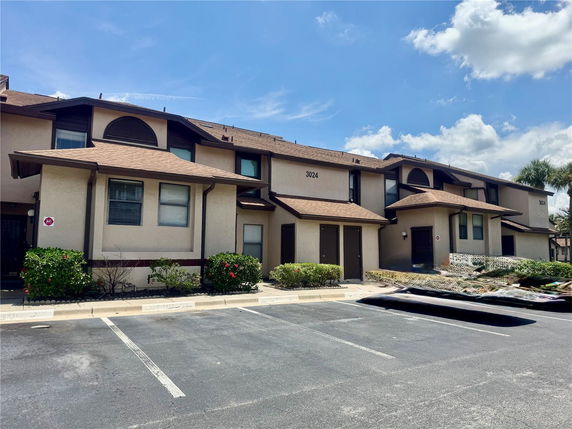 Front view of a two-story residential building with brown roof and light-colored exterior.