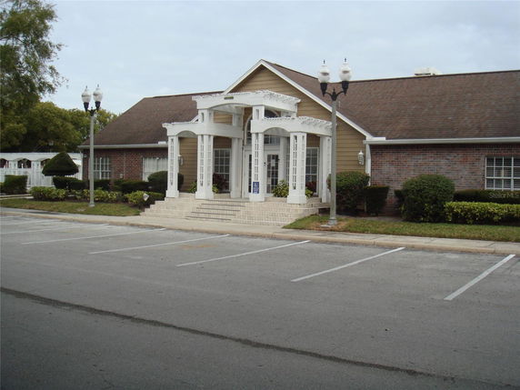 Front view of a single-story building with a prominent entrance and parking spaces.