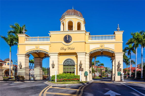 Front view of a grand entrance with a clock tower and gated archway.