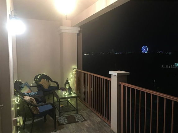Balcony view with seating area, overlooking city lights at night.