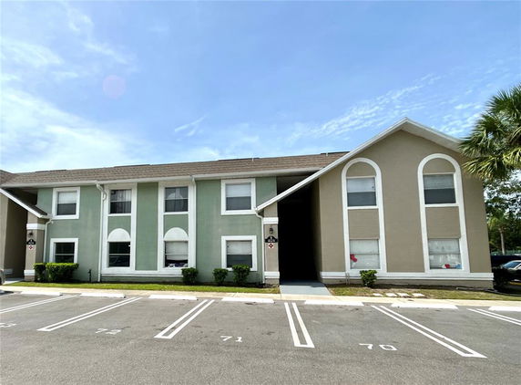 Front view of a two-story apartment building with multiple units and a parking area in front.