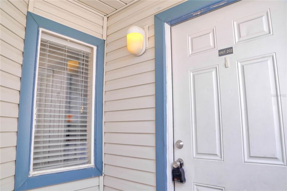 View of a building entrance with a white door labeled Unit 202, adjacent to a window with blinds.