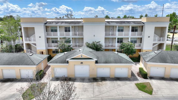 Front view of a three-story building with balconies and adjacent garage structures.