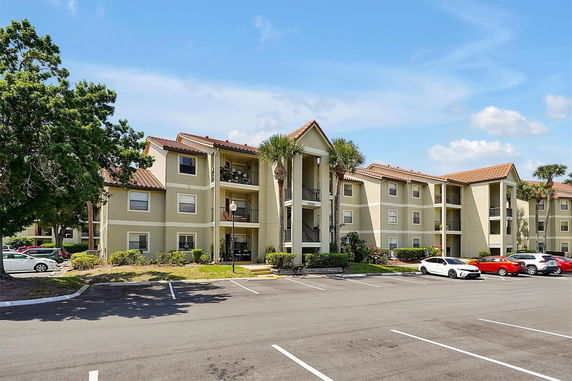 Front view of a three-story apartment building with balconies and a parking area.