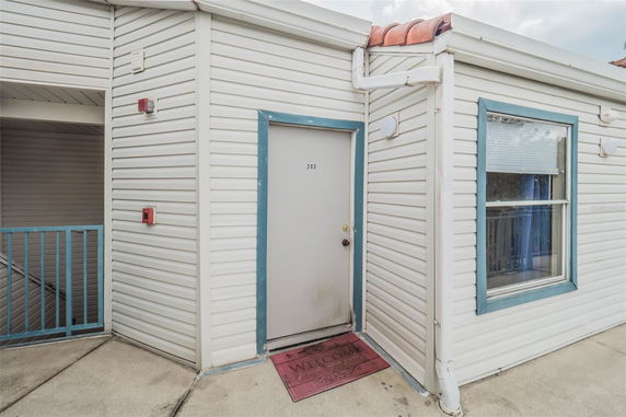 Front view of a building's entrance with a door labeled 203 and blue trim.