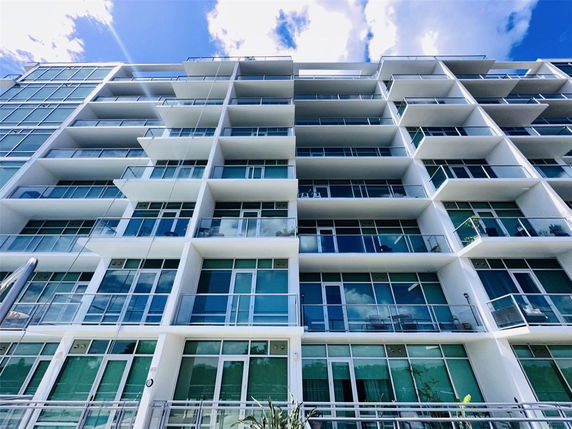 Front view of a modern multi-story apartment building with large glass balconies.