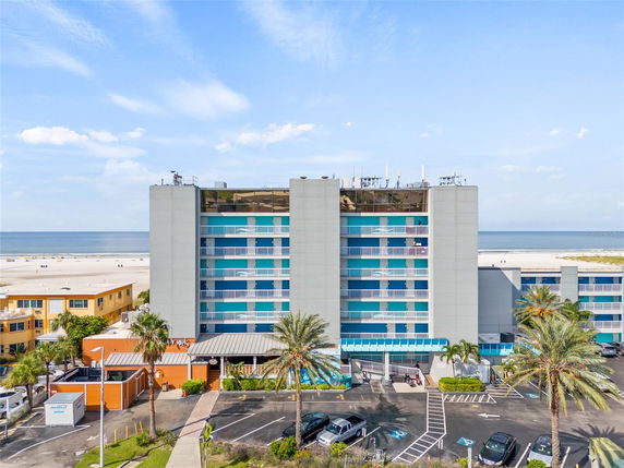 Front view of a multi-story beachfront building with a parking area.