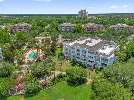 Panoramic view of a multi-story residential complex with a swimming pool and landscaped surroundings.