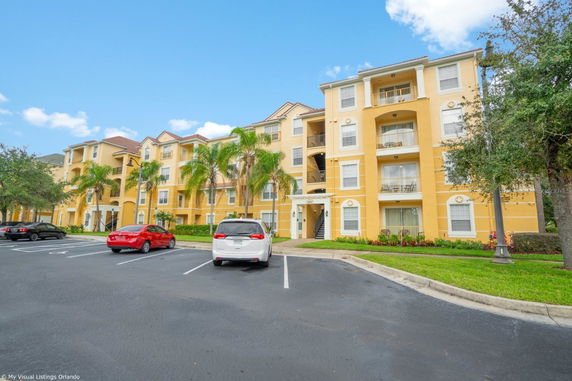 Front view of a multi-story apartment building with yellow exterior.